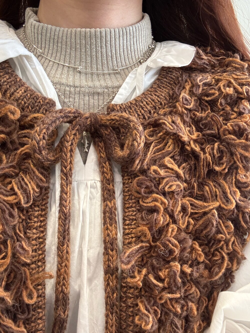 ブラウン系のベスト、シルバー系のネックレス、その他のチャームを着用したレディースの冬コーディネートの4枚目の写真