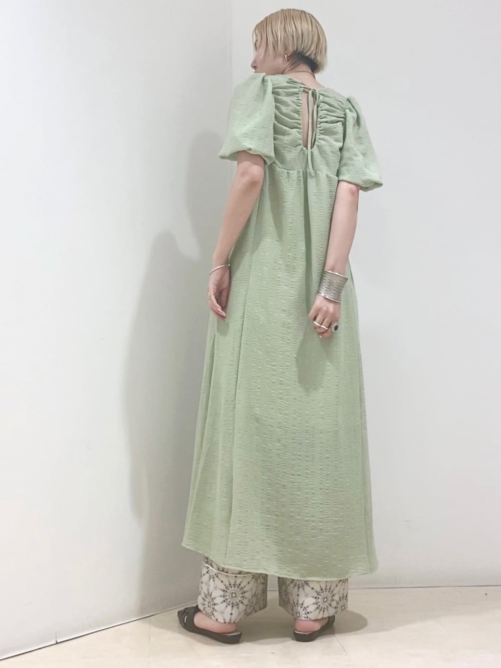 グリーン系のワンピース、ベージュ系のその他パンツ、ブラック系のサンダルを着用したレディースの春コーディネートの2枚目の写真