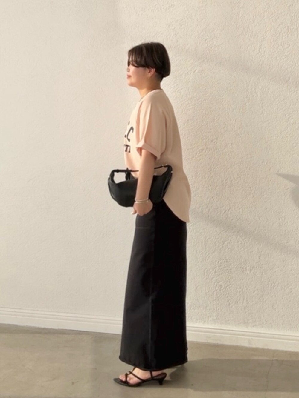 ピンク系のTシャツ/カットソー、ブラック系のスカート、ブラック系のショルダーバッグを着用したレディースの春コーディネートの2枚目の写真
