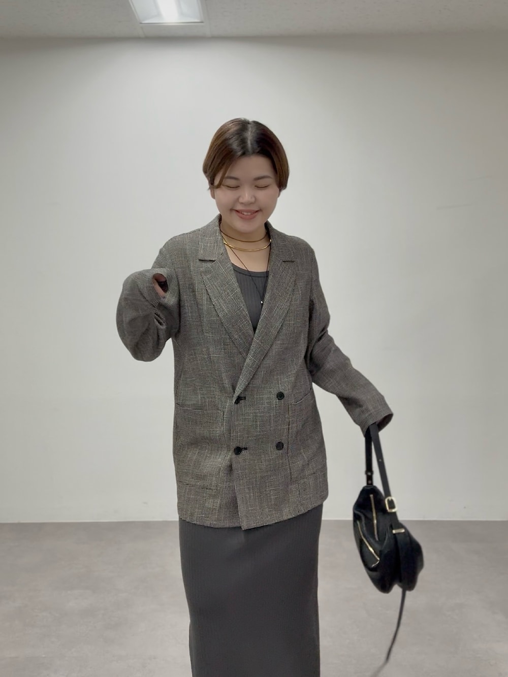 グレー系のワンピース、ブラック系のテーラードジャケットを着用したレディースの春コーディネートの3枚目の写真