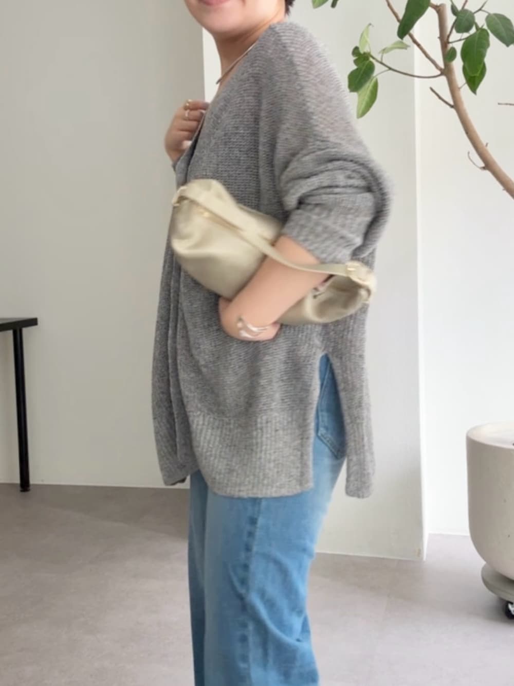 グレー系のカーディガン/ボレロ、ブルー系のデニムパンツ、ゴールド系のショルダーバッグを着用したレディースの春コーディネートの5枚目の写真