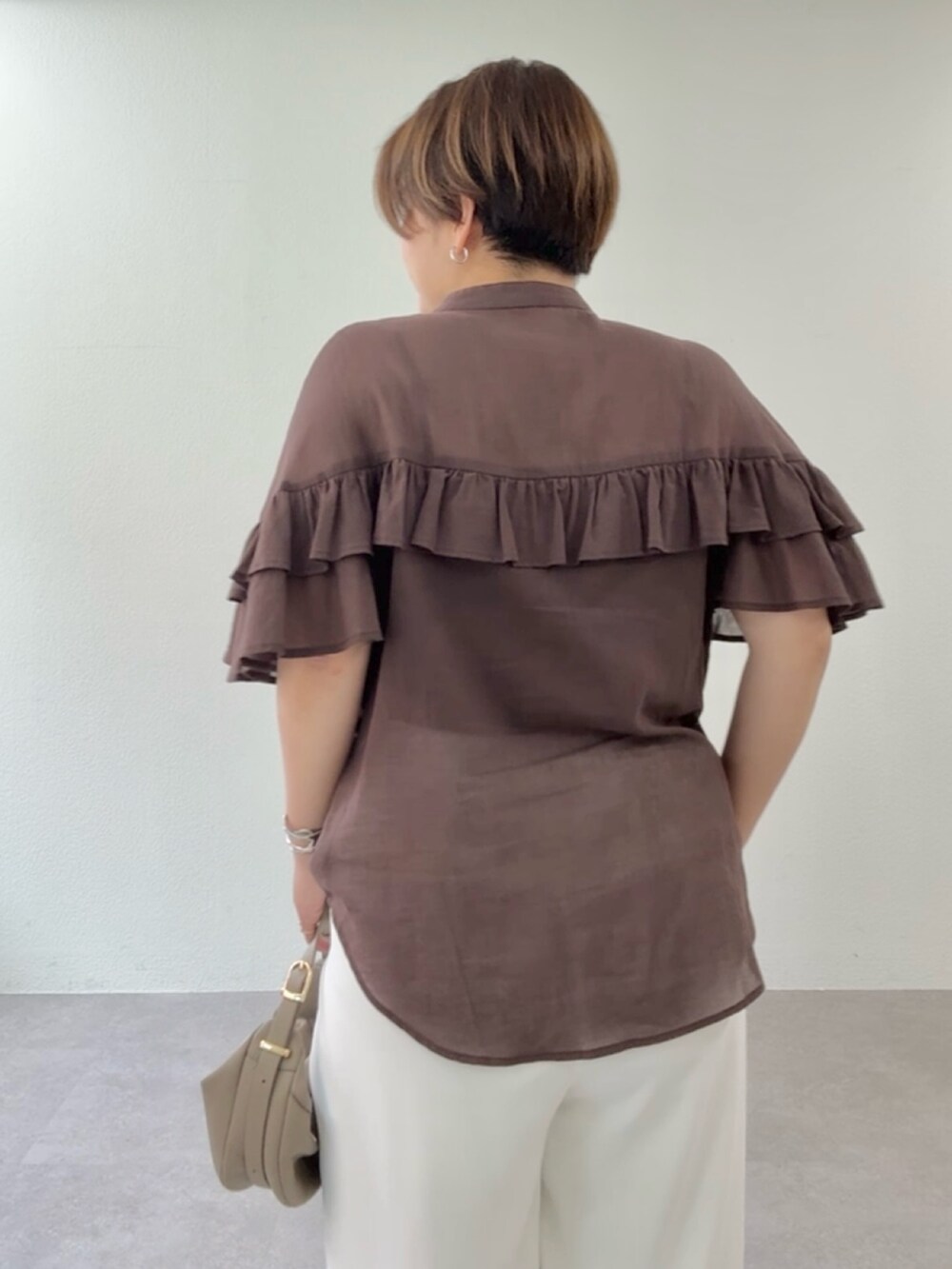 ブラウン系のシャツ/ブラウス、ホワイト系のスラックス、ベージュ系のショルダーバッグを着用したレディースの春コーディネートの4枚目の写真