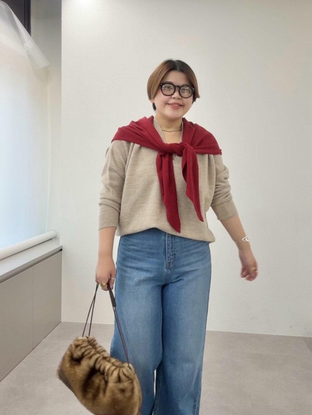 ベージュ系のニット/セーター、ブルー系のデニムパンツ、レッド系のストール/ショールを着用したレディースの冬コーディネートの4枚目の写真