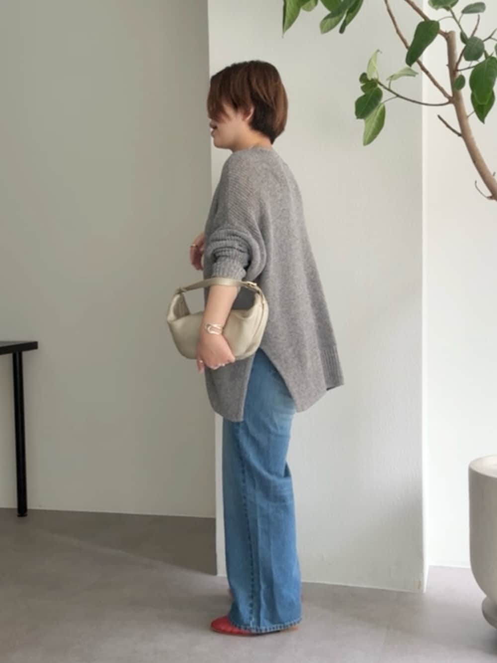 グレー系のカーディガン/ボレロ、ブルー系のデニムパンツ、ゴールド系のショルダーバッグを着用したレディースの春コーディネートの2枚目の写真