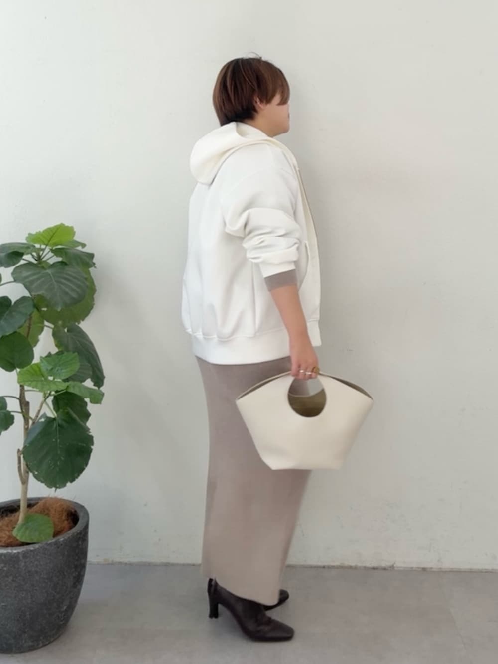 ホワイト系のパーカー、ブラウン系のニット/セーター、ブラウン系のスカートを着用したレディースの冬コーディネートの2枚目の写真