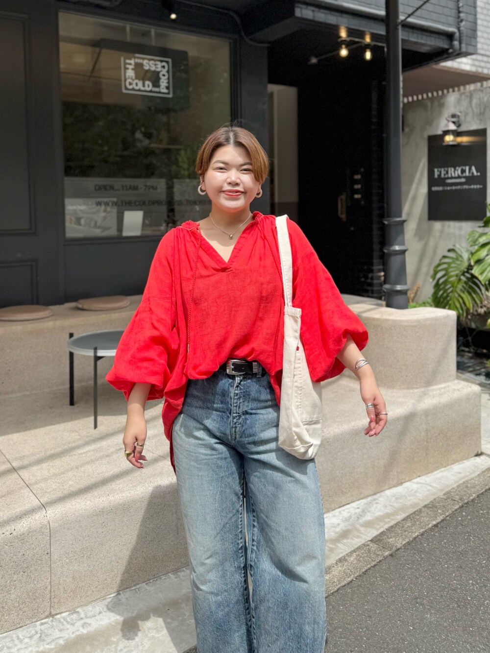 レッド系のシャツ/ブラウス、ブルー系のデニムパンツ、ホワイト系のハンドバッグを着用したレディースの春コーディネートの3枚目の写真