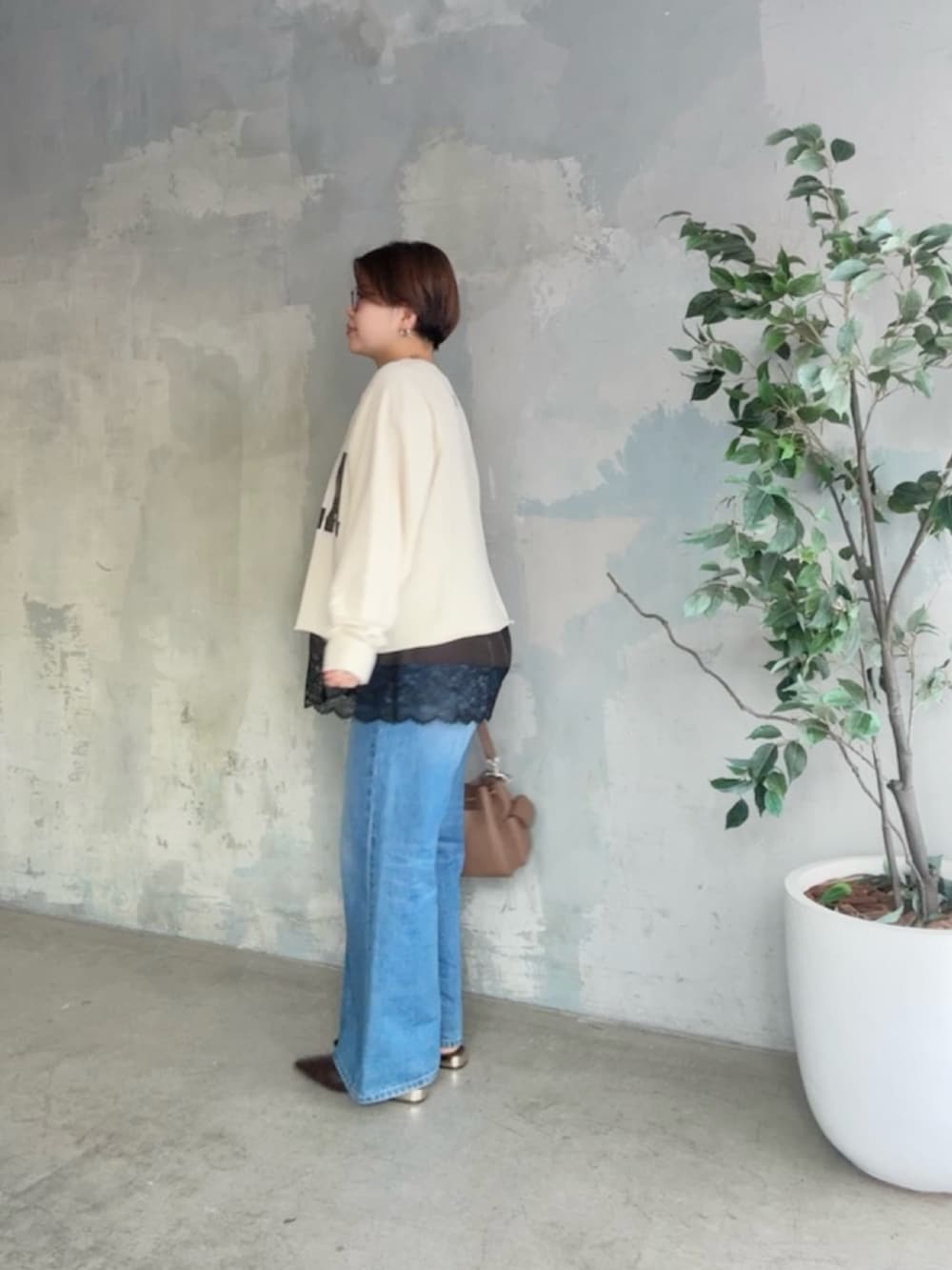 ホワイト系のスウェット、ブラウン系のキャミソール、ブルー系のデニムパンツを着用したレディースの冬コーディネートの3枚目の写真