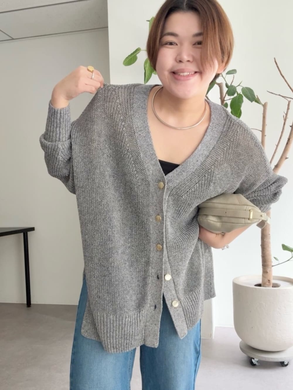 グレー系のカーディガン/ボレロ、ブルー系のデニムパンツ、ゴールド系のショルダーバッグを着用したレディースの春コーディネートの4枚目の写真