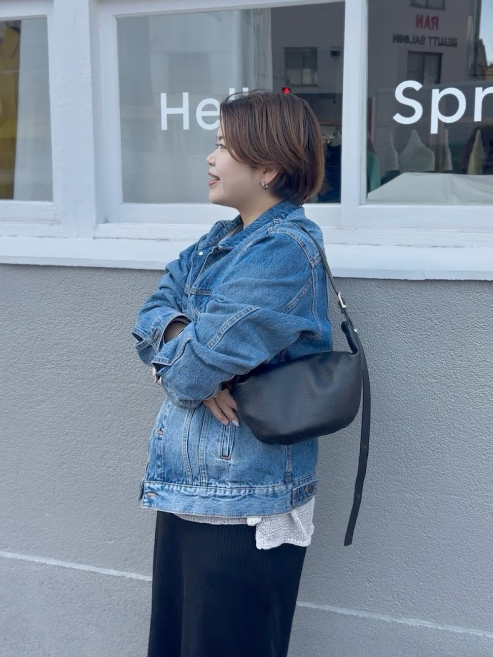 ブルー系のデニムジャケット、ブラック系のワンピース、グレー系のニット/セーターを着用したレディースの春コーディネートの3枚目の写真