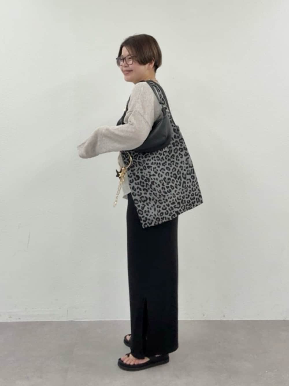 グレー系のニット/セーター、ブラック系のワンピースを着用したレディースの春コーディネートの2枚目の写真