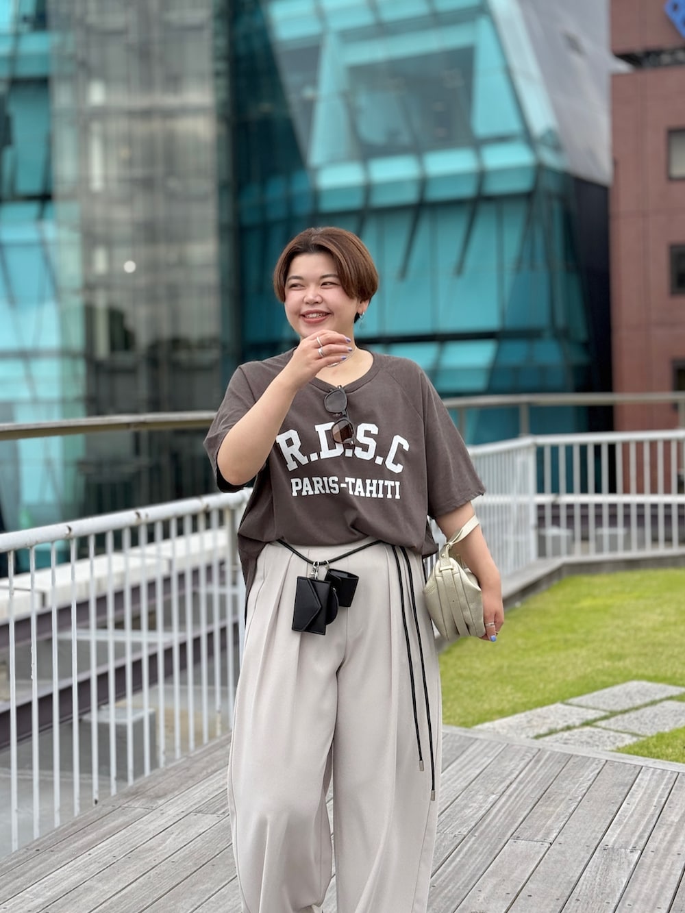 ブラウン系のTシャツ/カットソー、グレー系のスラックス、ゴールド系のショルダーバッグを着用したレディースの夏コーディネートの2枚目の写真