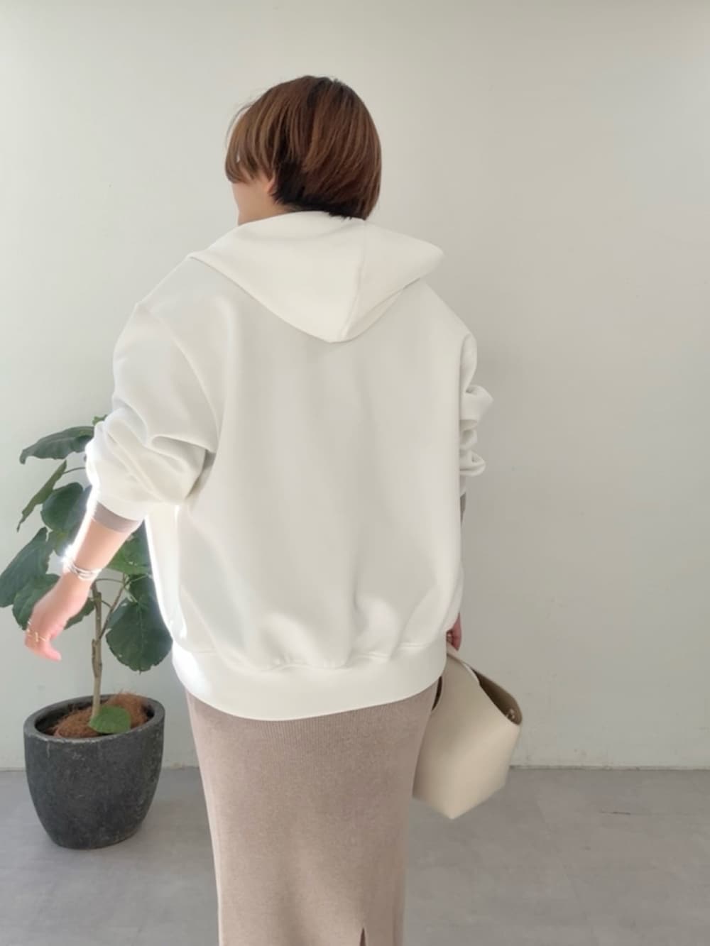 ホワイト系のパーカー、ブラウン系のニット/セーター、ブラウン系のスカートを着用したレディースの冬コーディネートの5枚目の写真