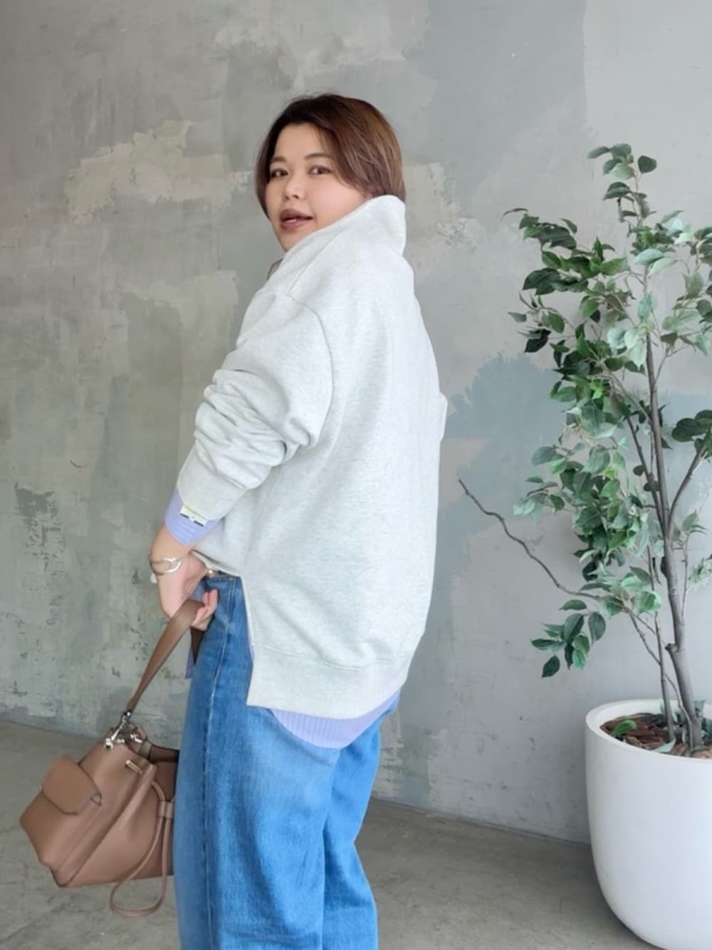 グレー系のスウェット、ブルー系のデニムパンツ、ブラウン系のショルダーバッグを着用したレディースの冬コーディネートの4枚目の写真