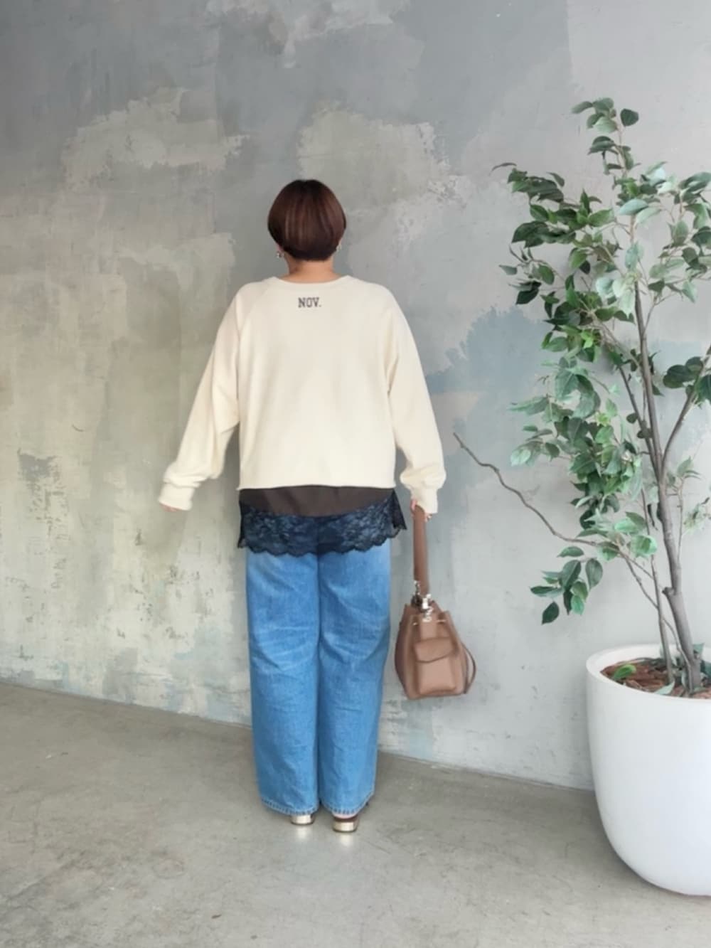 ホワイト系のスウェット、ブラウン系のキャミソール、ブルー系のデニムパンツを着用したレディースの冬コーディネートの4枚目の写真