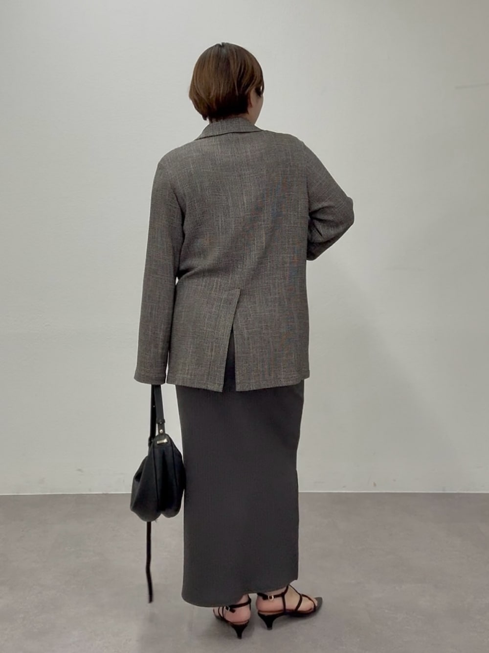 グレー系のワンピース、ブラック系のテーラードジャケットを着用したレディースの春コーディネートの2枚目の写真