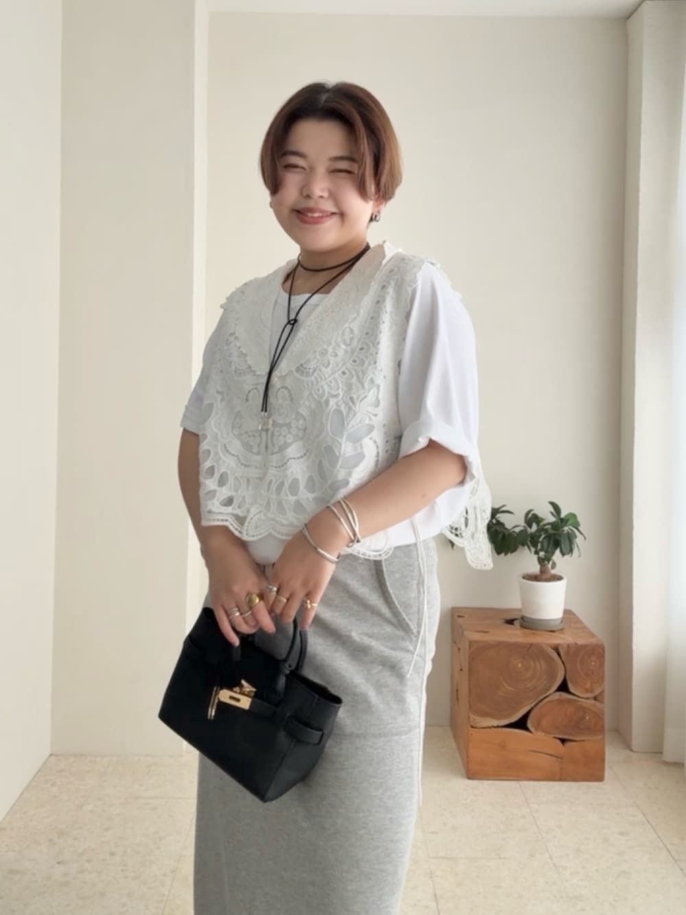 ホワイト系のTシャツ/カットソー、ホワイト系のベスト、グレー系のスカートを着用したレディースの夏コーディネートの3枚目の写真
