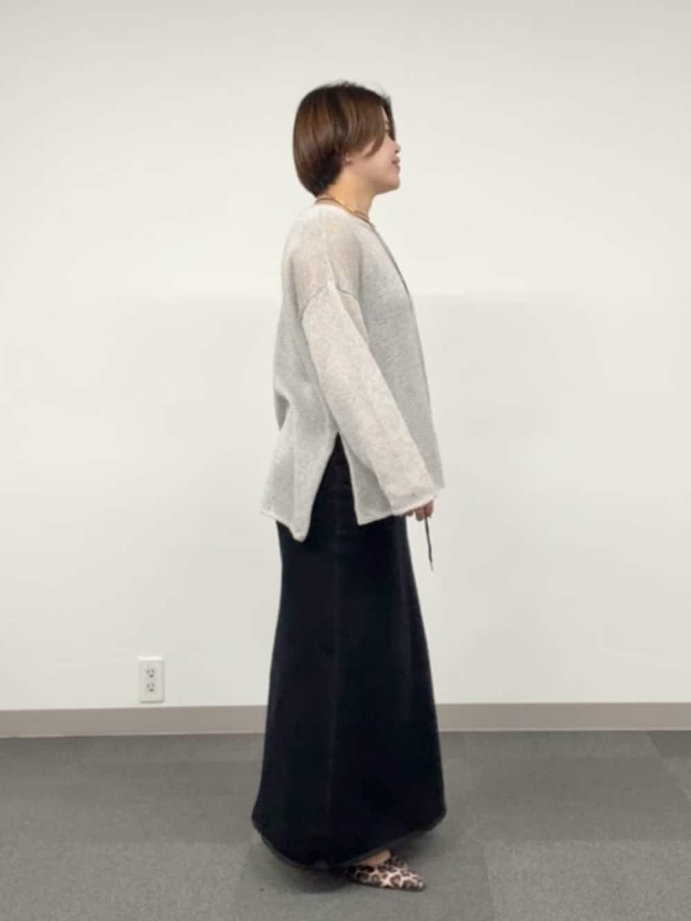 グレー系のニット/セーター、ブラック系のスカートを着用したレディースの春コーディネートの2枚目の写真