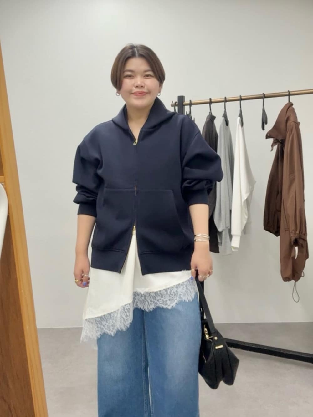 ブルー系のパーカー、ホワイト系のキャミソール、ブルー系のデニムパンツを着用したレディースの春コーディネートの5枚目の写真