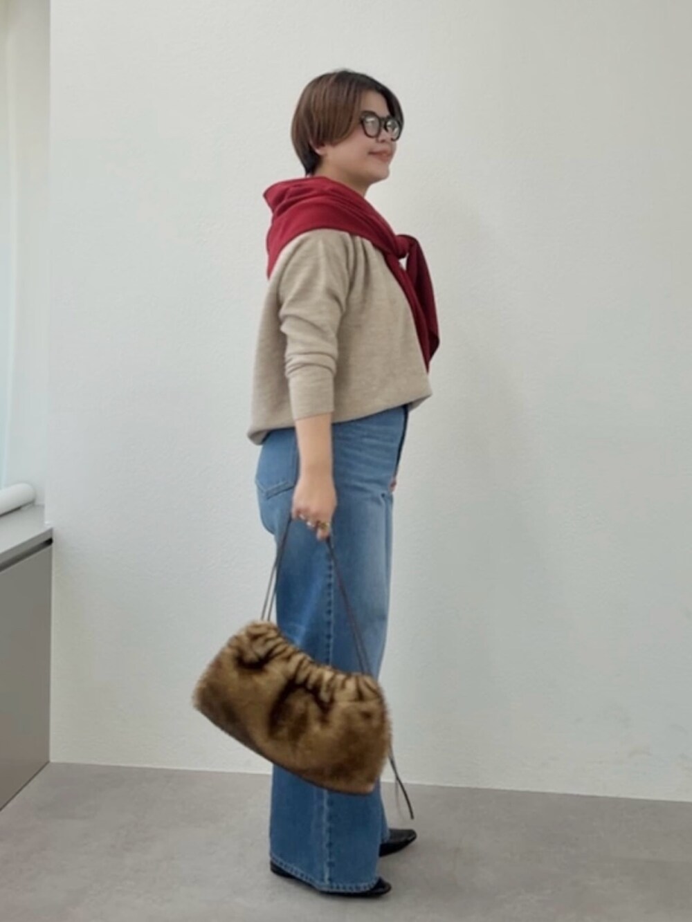 ベージュ系のニット/セーター、ブルー系のデニムパンツ、レッド系のストール/ショールを着用したレディースの冬コーディネートの2枚目の写真