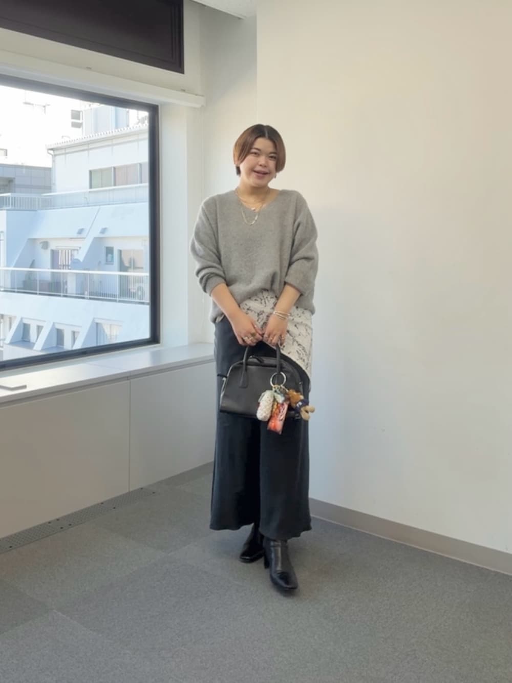 グレー系のニット/セーター、ブラック系のスカート、ホワイト系のストール/ショールを着用したレディースの冬コーディネートの2枚目の写真