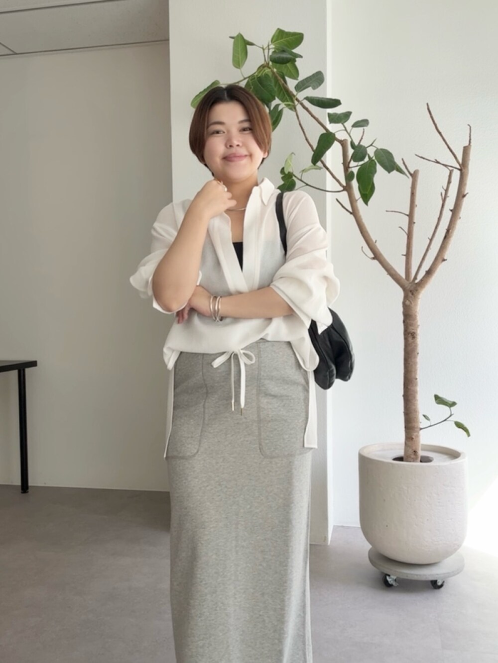 ホワイト系のシャツ/ブラウス、グレー系のスカート、ブラック系のショルダーバッグを着用したレディースの春コーディネートの4枚目の写真