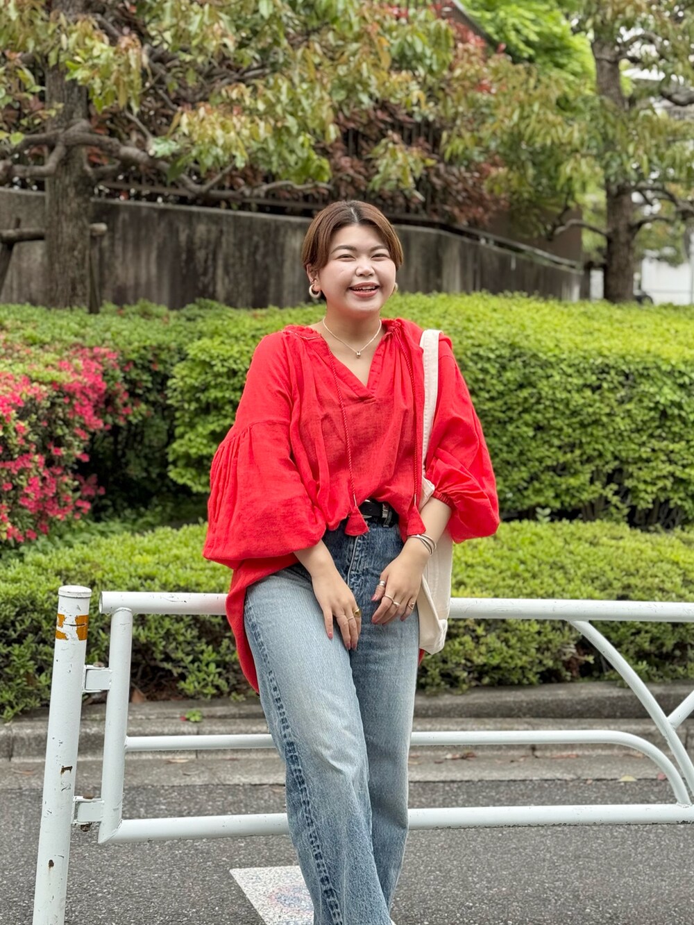 レッド系のシャツ/ブラウス、ブルー系のデニムパンツ、ホワイト系のハンドバッグを着用したレディースの春コーディネートの4枚目の写真