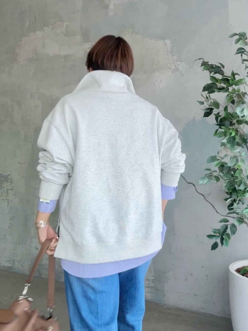 グレー系のスウェット、ブルー系のデニムパンツ、ブラウン系のショルダーバッグを着用したレディースの冬コーディネートの5枚目の写真