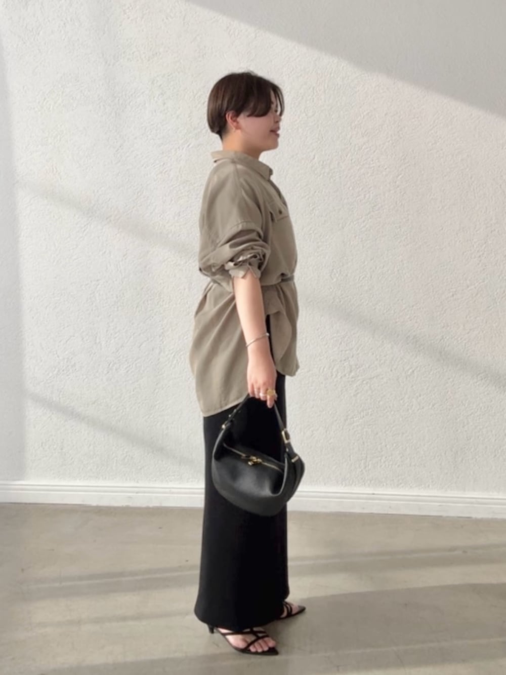 グリーン系のシャツ/ブラウス、ブラック系のワンピース、ブラック系のショルダーバッグを着用したレディースの春コーディネートの2枚目の写真