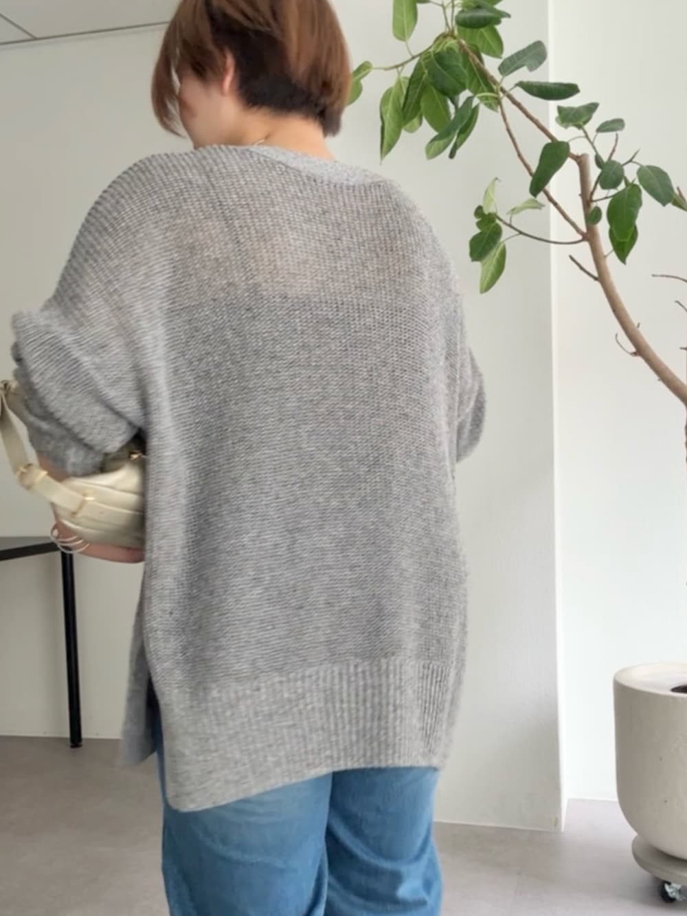 グレー系のカーディガン/ボレロ、ブルー系のデニムパンツ、ゴールド系のショルダーバッグを着用したレディースの春コーディネートの6枚目の写真