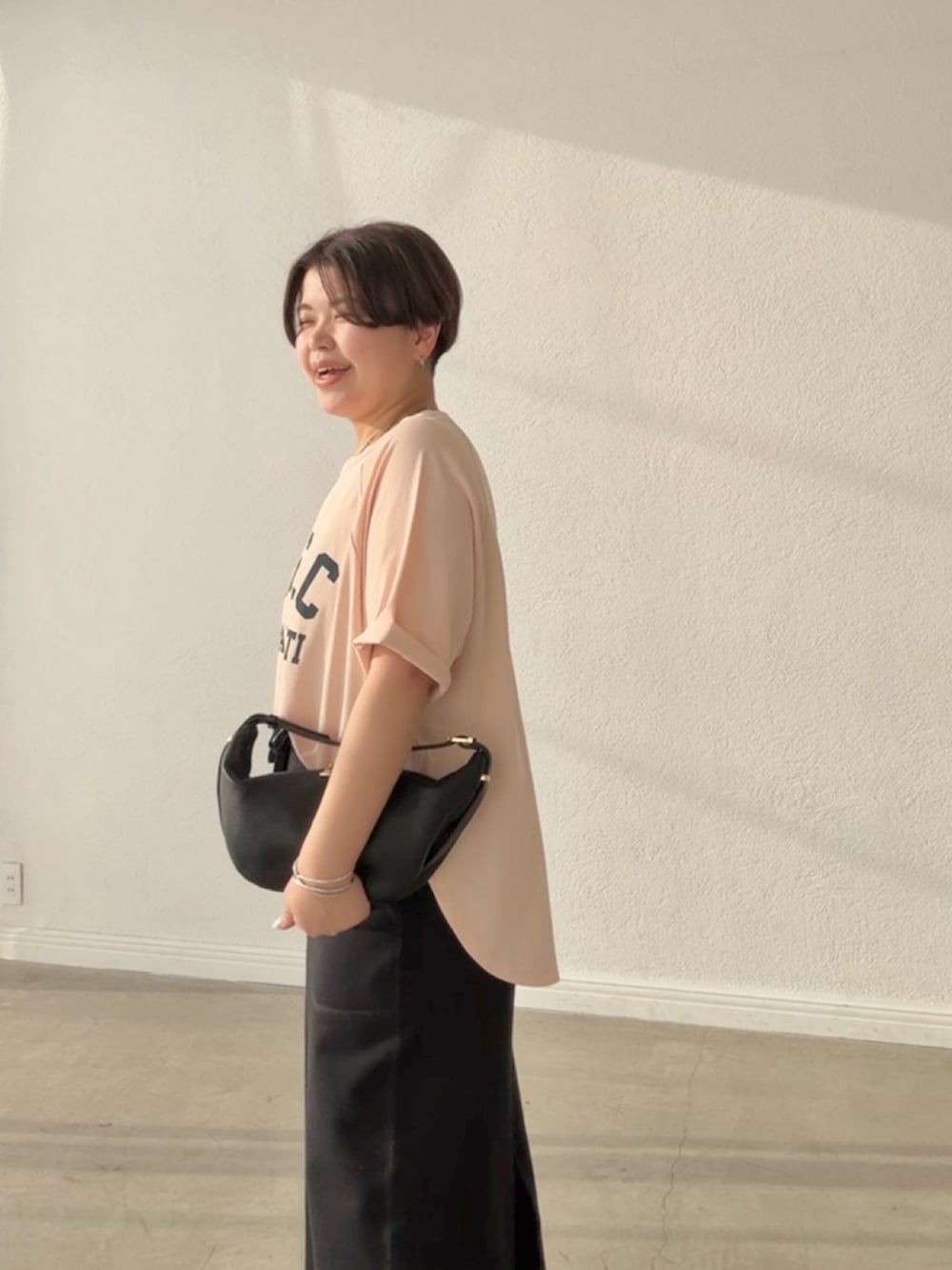 ピンク系のTシャツ/カットソー、ブラック系のスカート、ブラック系のショルダーバッグを着用したレディースの春コーディネートの5枚目の写真