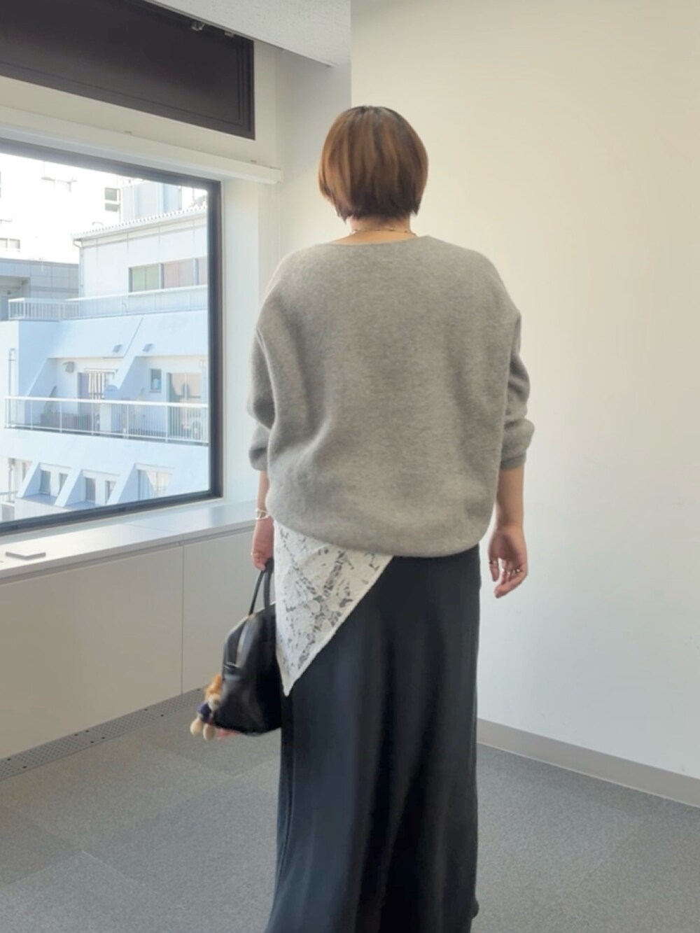 グレー系のニット/セーター、ブラック系のスカート、ホワイト系のストール/ショールを着用したレディースの冬コーディネートの5枚目の写真