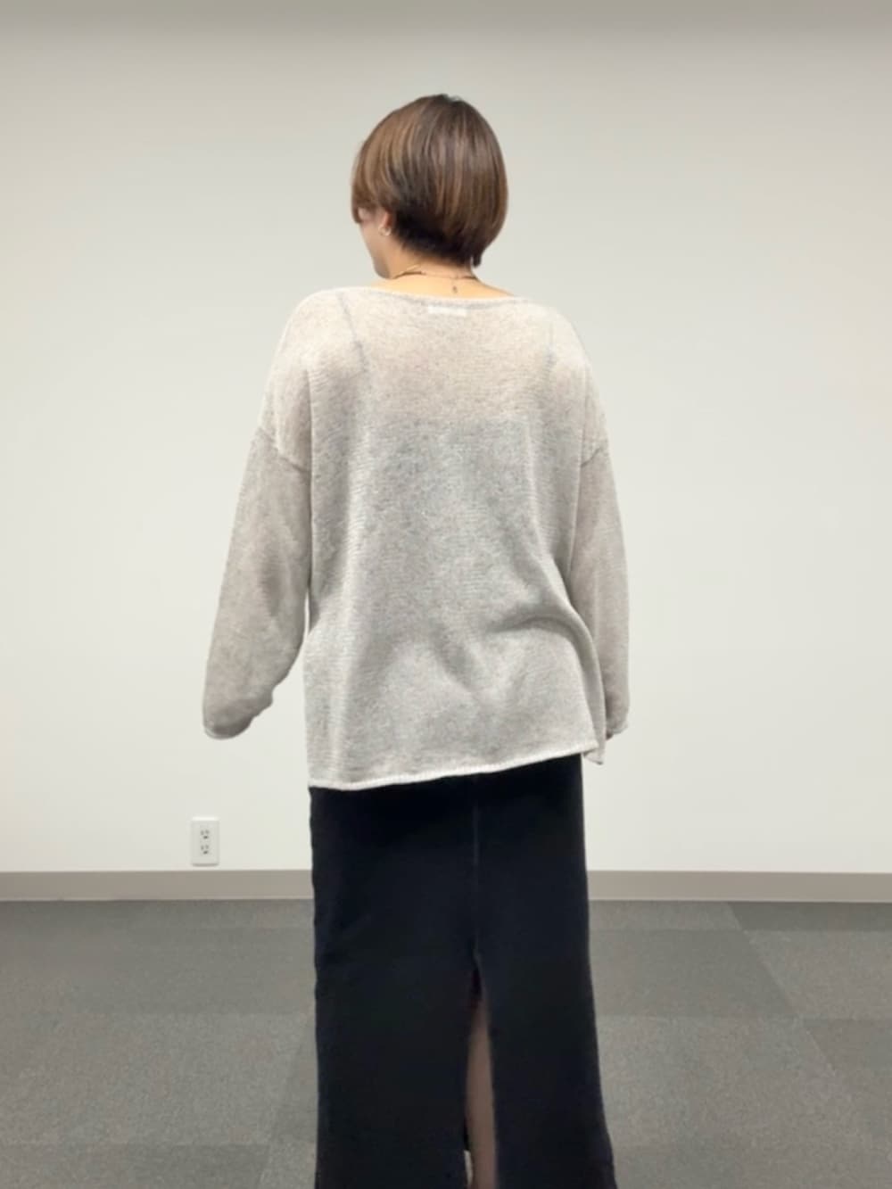 グレー系のニット/セーター、ブラック系のスカートを着用したレディースの春コーディネートの6枚目の写真