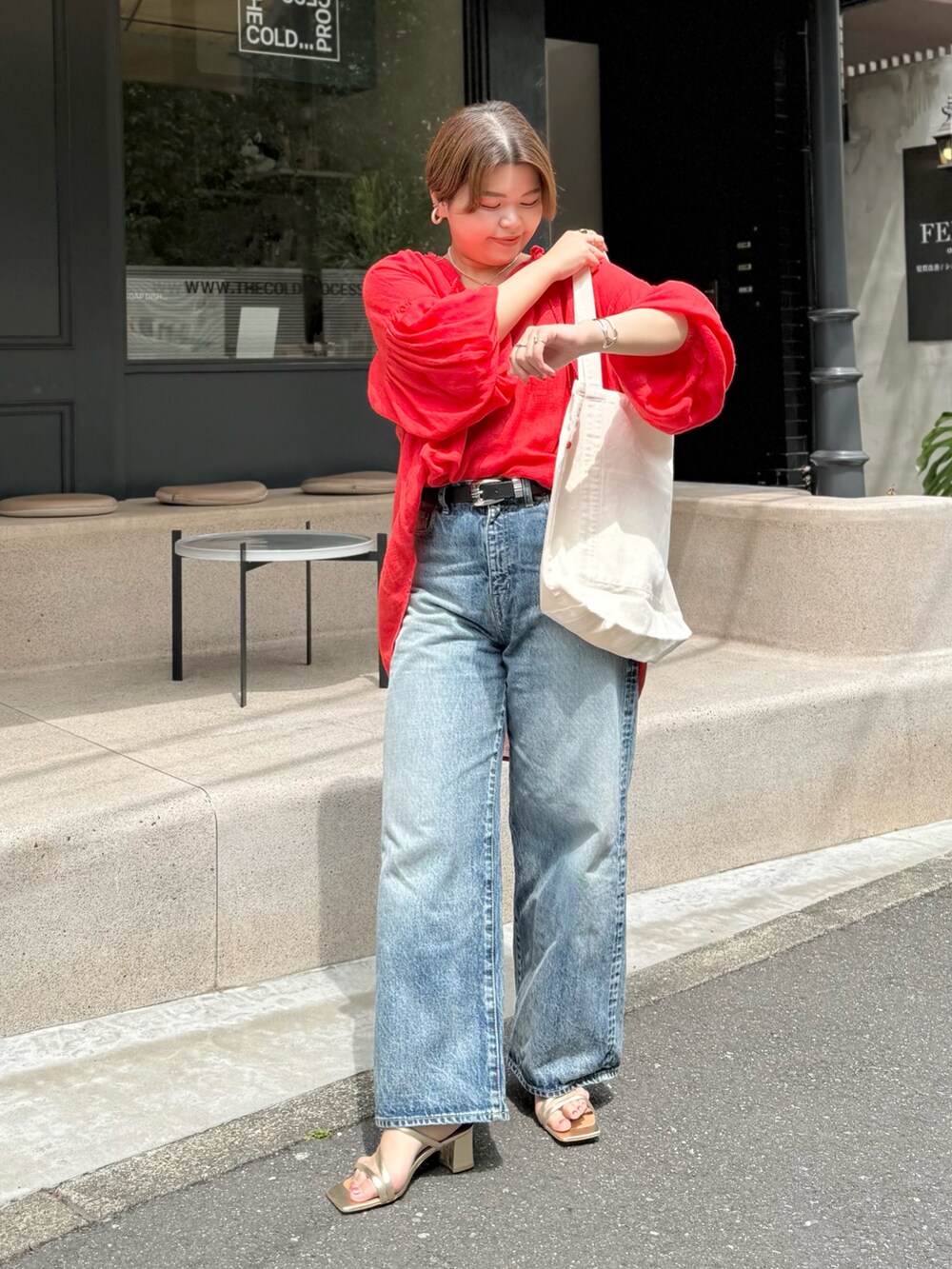 レッド系のシャツ/ブラウス、ブルー系のデニムパンツ、ホワイト系のハンドバッグを着用したレディースの春コーディネートの2枚目の写真