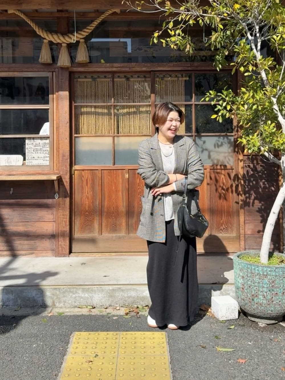 ブラック系のテーラードジャケット、グレー系のニット/セーター、ブラック系のワンピースを着用したレディースの春コーディネートの3枚目の写真