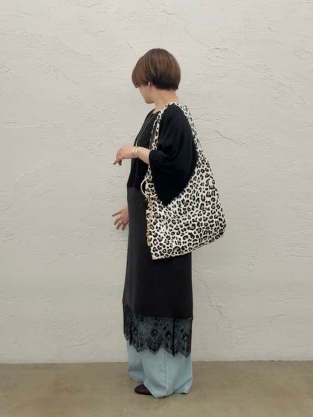 ブラック系のニット/セーター、ブラック系のワンピース、ブルー系のデニムパンツを着用したレディースの夏コーディネートの3枚目の写真