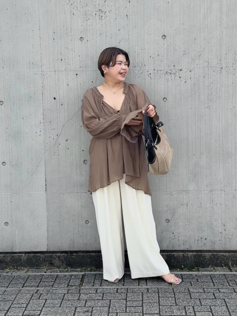 ブラウン系のシャツ/ブラウス、ホワイト系のスラックス、ブラウン系のトートバッグを着用したレディースの春コーディネートの4枚目の写真