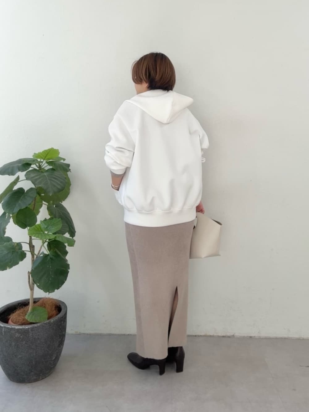 ホワイト系のパーカー、ブラウン系のニット/セーター、ブラウン系のスカートを着用したレディースの冬コーディネートの3枚目の写真