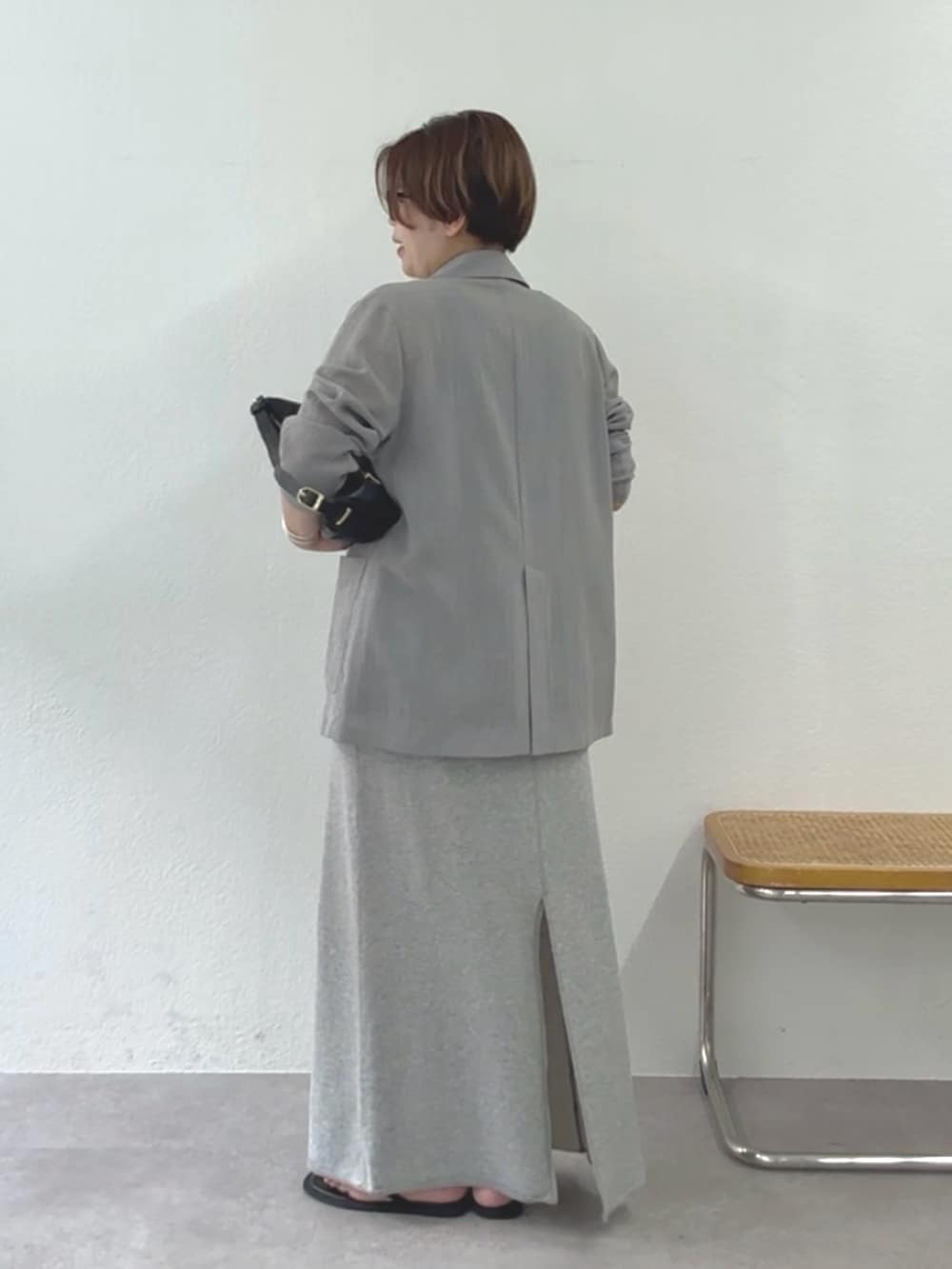 グレー系のテーラードジャケット、ブラック系のニット/セーター、グレー系のスカートを着用したレディースの夏コーディネートの3枚目の写真