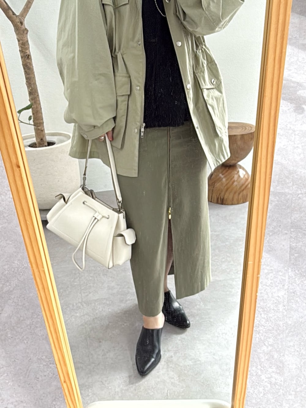 グリーン系のスカート、ブラック系のニット/セーター、グリーン系のブルゾンを着用したレディースの冬コーディネートの3枚目の写真