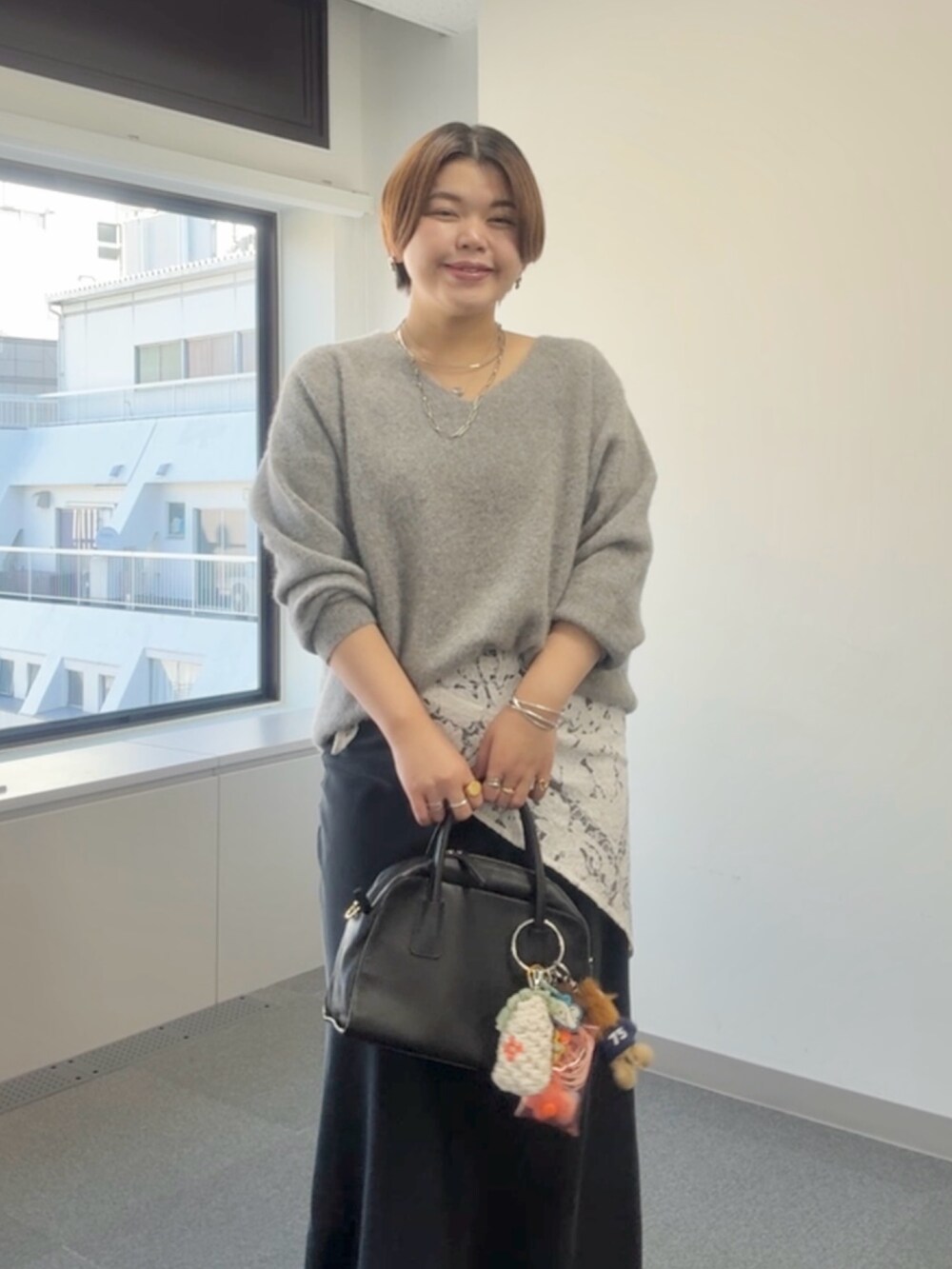 グレー系のニット/セーター、ブラック系のスカート、ホワイト系のストール/ショールを着用したレディースの冬コーディネートの3枚目の写真