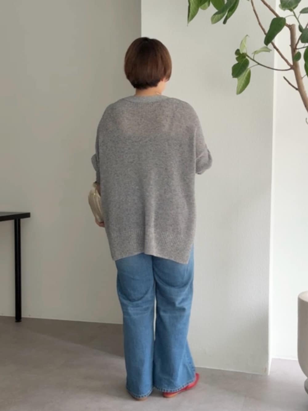 グレー系のカーディガン/ボレロ、ブルー系のデニムパンツ、ゴールド系のショルダーバッグを着用したレディースの春コーディネートの3枚目の写真