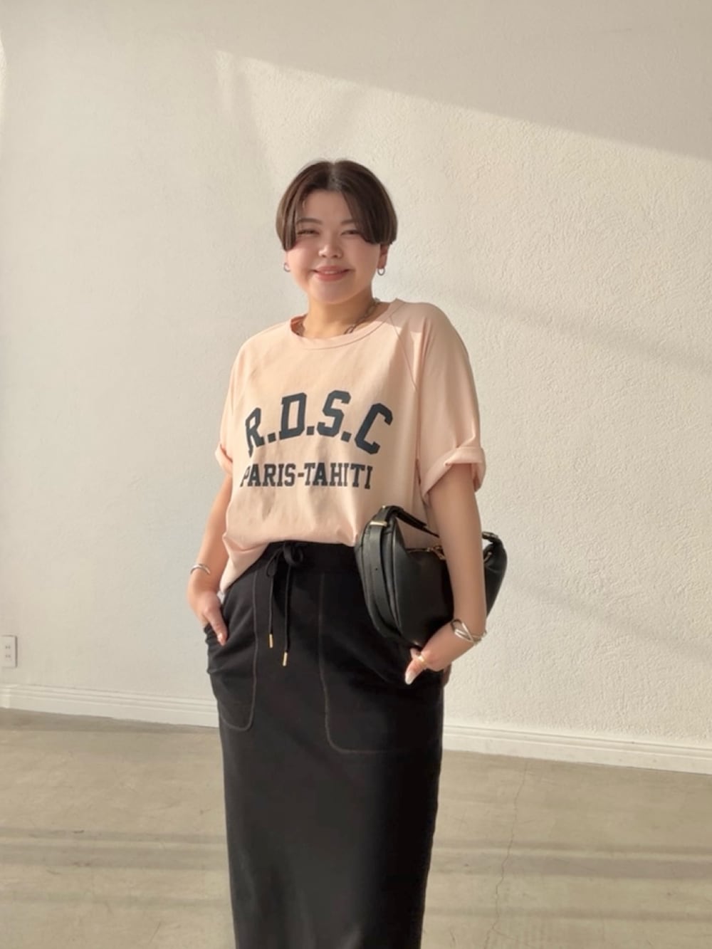 ピンク系のTシャツ/カットソー、ブラック系のスカート、ブラック系のショルダーバッグを着用したレディースの春コーディネートの4枚目の写真