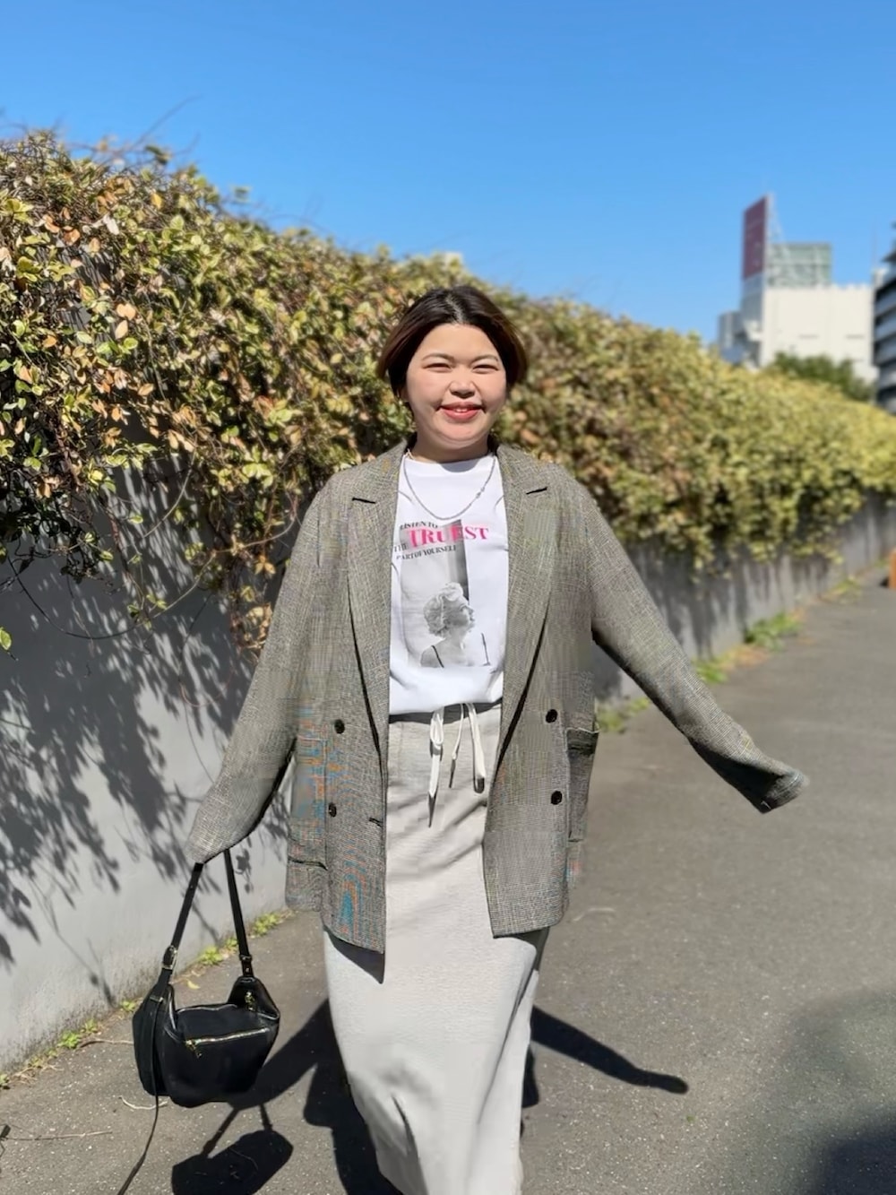 ホワイト系のTシャツ/カットソー、ブラック系のテーラードジャケット、グレー系のスカートを着用したレディースの春コーディネートの3枚目の写真