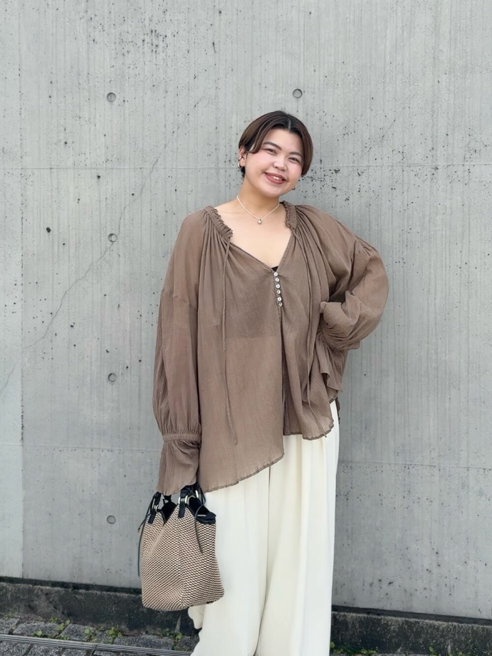 ブラウン系のシャツ/ブラウス、ホワイト系のスラックス、ブラウン系のトートバッグを着用したレディースの春コーディネートの3枚目の写真