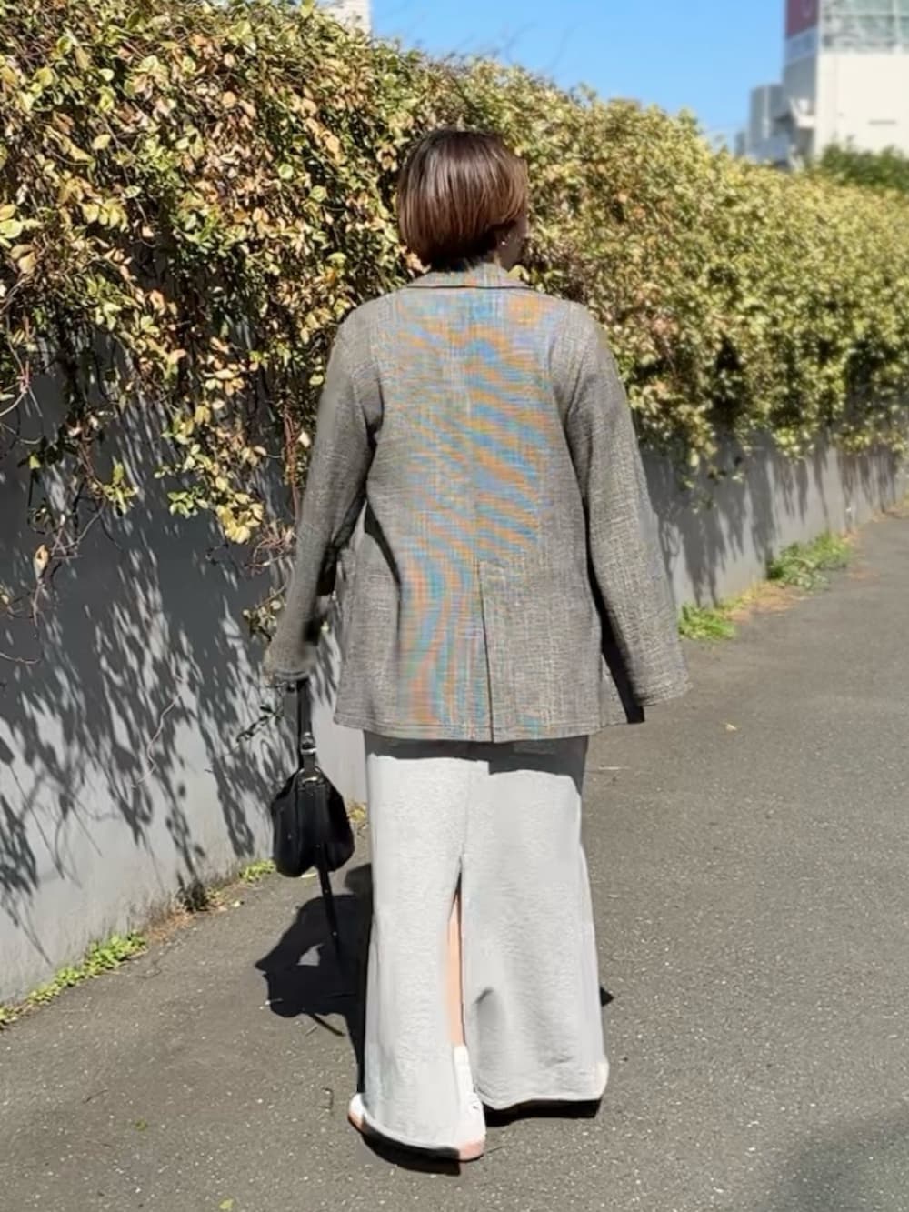 ホワイト系のTシャツ/カットソー、ブラック系のテーラードジャケット、グレー系のスカートを着用したレディースの春コーディネートの2枚目の写真