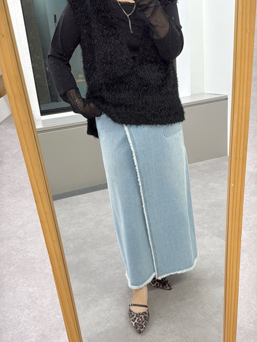 ブラック系のベスト、ブラック系のTシャツ/カットソー、ブルー系のスカートを着用したレディースの冬コーディネートの3枚目の写真