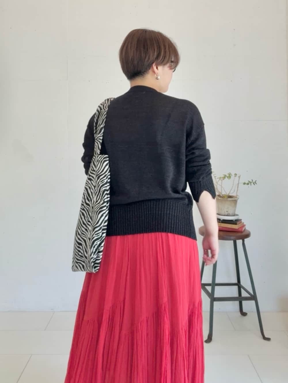 ブラック系のカーディガン/ボレロ、レッド系のスカート、ブラック系のトートバッグを着用したレディースの春コーディネートの6枚目の写真