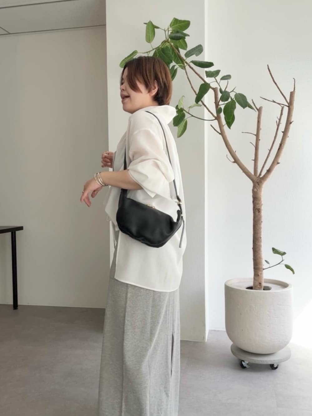 ホワイト系のシャツ/ブラウス、グレー系のスカート、ブラック系のショルダーバッグを着用したレディースの春コーディネートの5枚目の写真