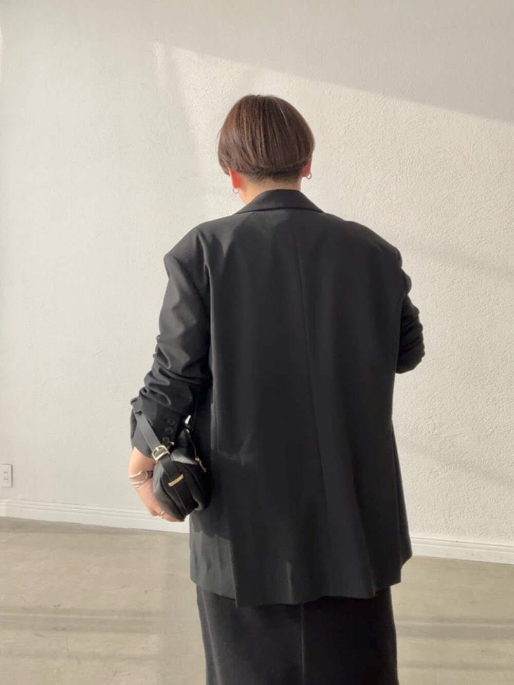 ブラック系のテーラードジャケット、ブラック系のスカート、ピンク系のTシャツ/カットソーを着用したレディースの春コーディネートの6枚目の写真