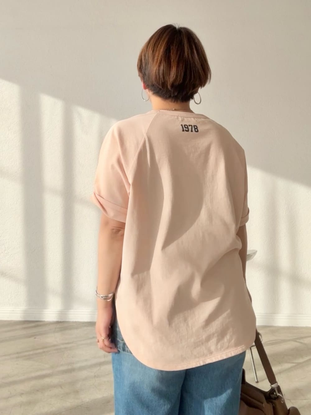 ピンク系のTシャツ/カットソー、ブルー系のデニムスカート、ブルー系のデニムパンツを着用したレディースの春コーディネートの6枚目の写真